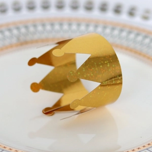 Close-up of golden crown napkin ring with sparkling glitter finish on a white plate