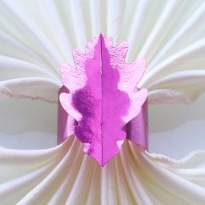 Détail d'un rond de serviette feuille d'érable rose brillant sur de la soie blanche
