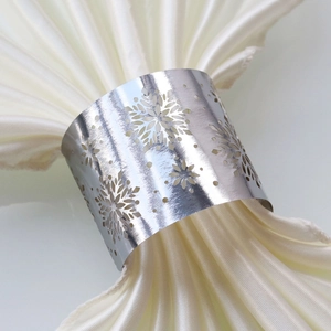 Detail of silver snowflake napkin ring with intricate hollow design on silk cloth