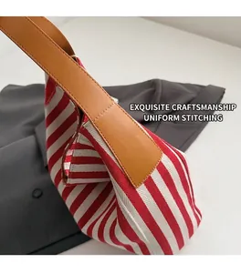 Close-up of red and white striped canvas tote with brown leather straps and stitching
