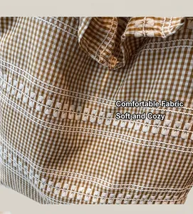 Détail du tissu en toile avec motif vichy marron et broderie ondulée blanche