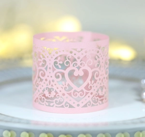 Close-up of pink laser-cut paper napkin ring with intricate heart pattern for weddings