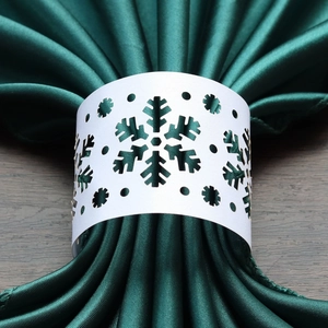 Detailed close-up of white snowflake laser-cut paper napkin ring on green satin