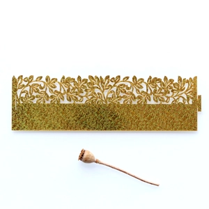 Close-up of golden glitter napkin ring with laser-cut leaf and vine patterns