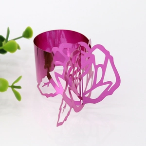Detail showing the cutout rose pattern napkin ring in vibrant magenta with metallic finish