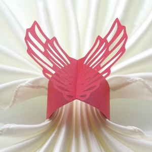 Detail of red laser-cut butterfly wing napkin ring on white satin fabric