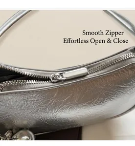 Detail of silver metallic handbag showing smooth zipper closure and pleated texture