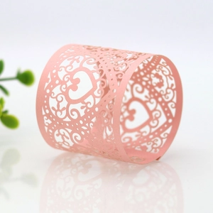 Macro view of a pink laser-cut paper napkin ring with elegant floral heart patterns