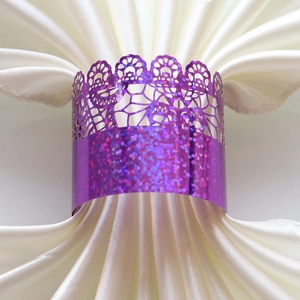 Macro shot of purple laser-cut napkin ring with glitter finish on a satin fabric