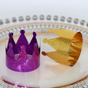 Detail of laser crown napkin rings in purple and gold glitter for party table settings