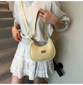 Detail of light beige crescent shoulder bag with crocodile pattern and silver metal hardware