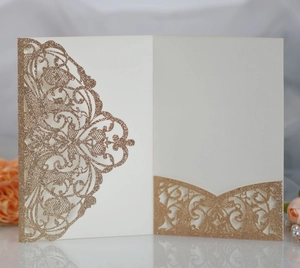 Close-up of laser-cut lace champagne gold wedding invitation card with glitter finish