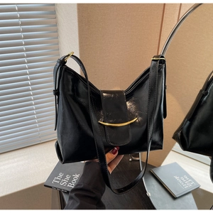 Detail of black glossy faux leather bag with gold curved metal clasp and pleated structure