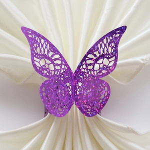 Close-up of laser-cut purple butterfly napkin ring with glitter on white silk fabric