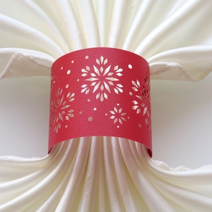 Close-up of laser-cut red snowflake napkin ring on white satin fabric for Christmas table