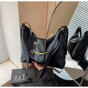 Detailed close-up of shiny black crescent bag featuring a golden metallic buckle