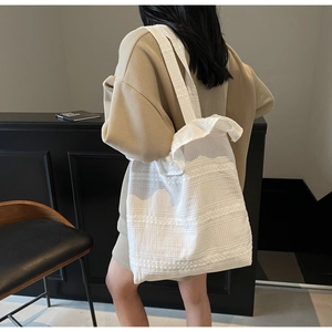 Gros plan sur un sac cabas en toile blanche avec tissu plissé et large bandoulière