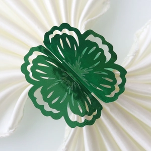Macro shot of dark green laser-cut flower napkin ring on white fabric background