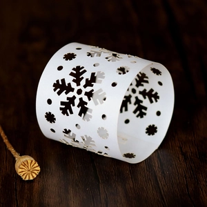 Close-up of laser-cut white paper napkin ring with snowflake pattern for holiday decor