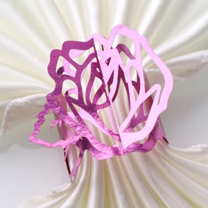 Macro view of metallic rose flower napkin ring with delicate hollow petals for weddings