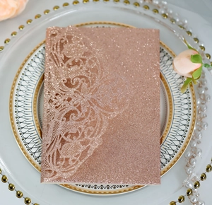 Detail of laser cut lace patterns on a champagne gold glitter wedding invitation card
