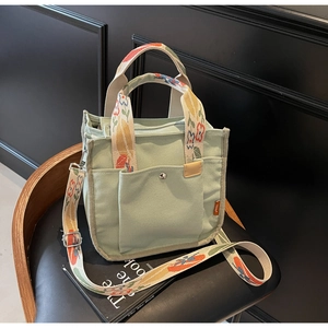 Detail of mint green canvas tote bag with floral handles and metal snap front pocket