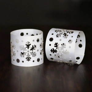 Detailed laser-cut white snowflake napkin ring on a dark rustic wooden table