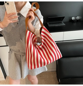 Detail of red and white striped canvas tote bag with brown leather handles