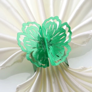 Close-up of green butterfly napkin ring with hollow wings on white silk napkin