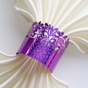 Close-up of laser-cut purple glitter napkin ring with intricate floral vine hollow design