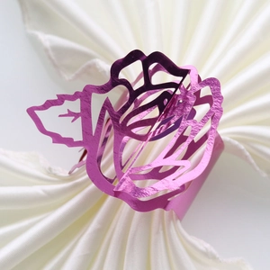 Close-up of laser-cut rose paper napkin ring with metallic rose red finish and leaf detail