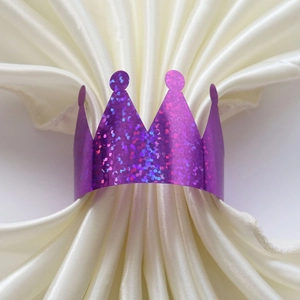 Macro detail of purple glitter crown napkin ring on white pleated silk fabric