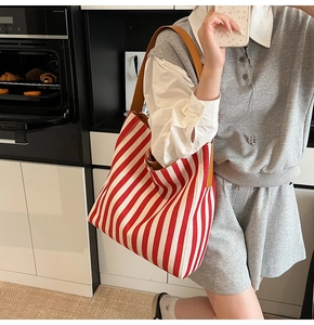 Detail of red and white striped canvas tote bag with brown handles in a home setting