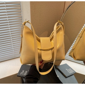 Detail of minimalist pale yellow hobo bag with gold metal arc and leather texture