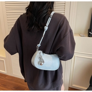 Detail of light blue crescent shoulder bag with knotted strap and silver orb pendant