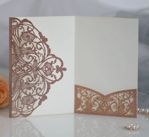 Close-up of rose gold laser-cut wedding invitation with fine glitter and mandala patterns