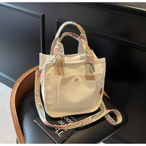 Detail of floral embroidery on the white canvas tote bag with adjustable shoulder strap