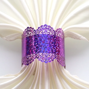 Detail of purple sequin napkin ring with laser-cut lace pattern on white satin