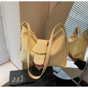 Detail of cream leather hobo bag featuring gold semi-circular hardware and smooth texture
