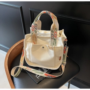 Detail of white canvas tote with colorful patterned strap and metal snap pocket