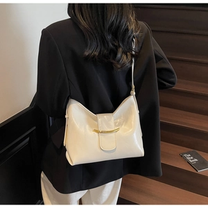 Chic beige leather shoulder bag with gold metal hardware shown on model in a sleek blazer