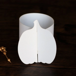 Close-up of elegant 3D white paper pumpkin napkin ring on a dark wooden table background