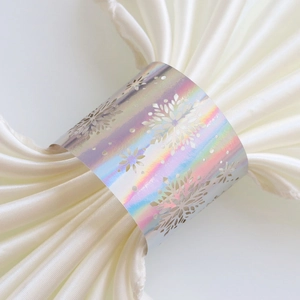 Close-up of holographic snowflake napkin ring with laser-cut hollow design on white fabric