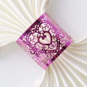 Close-up of purple laser-cut heart napkin ring with floral vines on white cloth