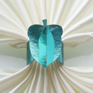 Detailed view of blue metallic leaf napkin ring on elegant cream fabric for parties
