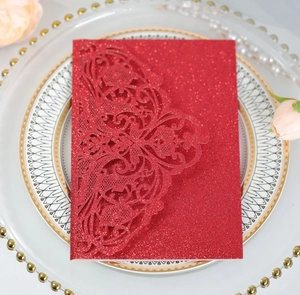 Macro shot of laser-cut lace floral pattern on glittery red wedding invitation card