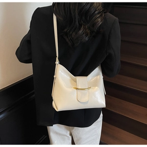 Detail view of cream white leather bag with gold U-shaped buckle and adjustable strap