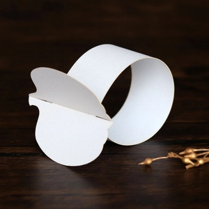 Macro shot of white pearlescent paper napkin rings with elegant scalloped edges on wood