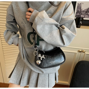 Detailed macro view of the black pleated crescent bag with a silver balloon dog charm