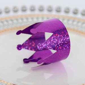 Close-up of a purple glitter crown napkin ring on a white plate with gold rim